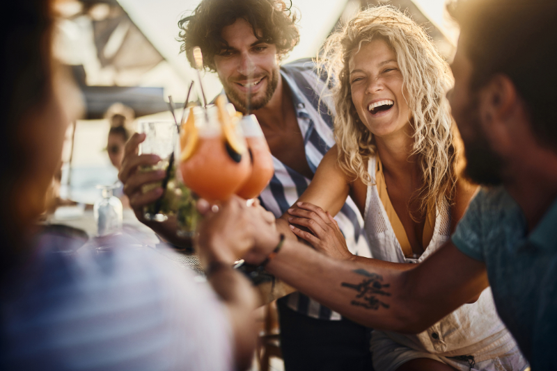 Cheerful friends toasting with cocktails in summer day